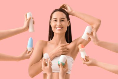Güzel, genç, mutlu bir kadın ve pembe arka planda farklı deodorantları olan eller.