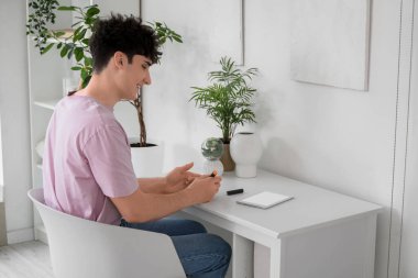 Şeker hastası genç adam evde tablet bilgisayarlı tükenmez kalem kullanıyor.