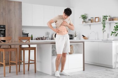 Şeker hastası genç adam mutfakta kendine insülin iğnesi yapıyor.