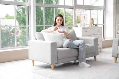 Şeker hastası genç bir kadın evdeki kanepede tükenmez kalem kullanıyor.