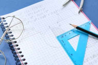 Mavi arkaplanda gözlüklü ve okul kırtasiyeli defter, yakın plan