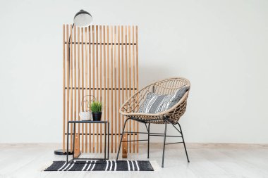 Rahat koltuğu, sehpası, lambası ve katlanır ekranı olan şık bir oturma odası.