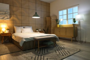 Yatak odasının içi, büyük yatak odası, çekmeceler, komodinlerle ve geceleri parlayan lambalarla dolu.