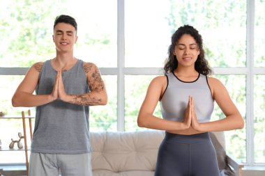 Evde birlikte yoga yapan genç bir çift.