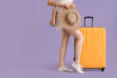 Bavullu, çantalı ve sarı şapkalı genç bir kadın.