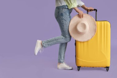 Leylak arka planda bavulu ve şapkası olan genç bir kadın.