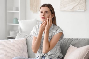 Evde diş ağrısı çeken genç bir kadın.
