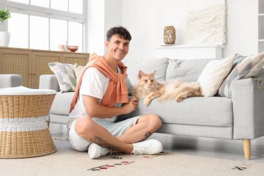 Evde sevimli Maine Coon kedisi olan yakışıklı, genç ve mutlu bir adam.