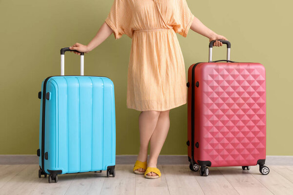 Молодая женщина с чемоданами на зеленом фоне