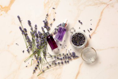 Lavanta şişeleri esaslı yağ ve kavanozla mermer arka planda kurumuş çiçekler.
