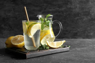 Siyah arka planda naneli bir bardak taze limonata.