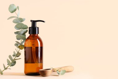 Ahşap kaşık ve bir şişe okaliptüs esaslı yağ bej arka planda, yakın plan.