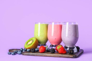 Leylak arka planında farklı meyveler olan taze meyve püresi.