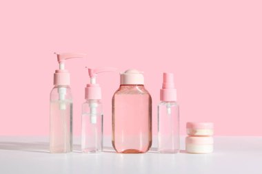 Seyahat kozmetik ürünleri, pembe arka planda hafif masa üzerinde