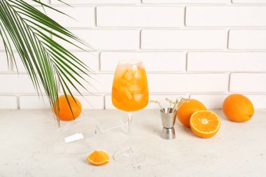 Beyaz masa üzerinde palmiye yaprağı ve portakallı Aperol spreyi kokteyli.