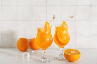 Beyaz masada Aperol spreyli kokteyl ve portakallar.