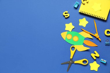 Mavi arka planda okul kırtasiyesi olan kağıt roket