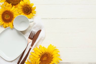 Beyaz ahşap arka planda ayçiçekleri olan güzel bir masa.