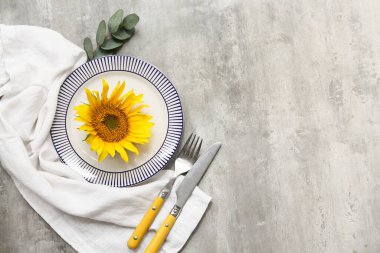 Gri arka planda okaliptüs ve ayçiçeğiyle güzel bir masa.