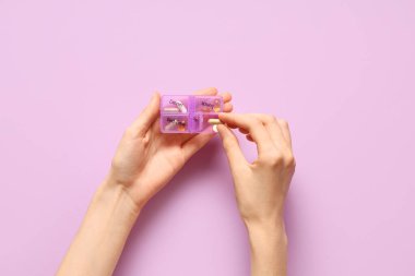 Leylak arka planında hap organizatörleri olan bir kadın eli. Üst görünüm