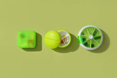 Yeşil arka planda haplar olan plastik kaplar. Üst görünüm