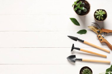 Beyaz ahşap arka planda tırmık, kürek ve budama aletleri. Üst görünüm