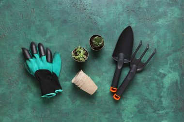 Kürekli bahçe malzemeleri, turba kapları ve yeşil grunge arka planda eldivenler. Üst görünüm