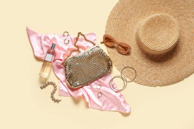 Güneş gözlüklü, parfümlü ve bej arka planda ipek pembe kumaşlı şık aksesuarlar. Üst görünüm