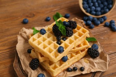 Taze yaban mersini, böğürtlen ve ahşap zemin üzerinde nane şekerli Belçika waffleları.