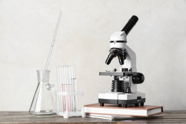 Kimyasal şişelerle modern mikroskop ve beyaz grunge arka planına karşı ahşap masa üzerine kitap