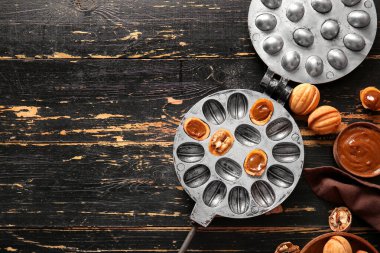 Lezzetli ceviz şekilli kurabiyeler ve koyu ahşap zemin üzerinde kaynatılmış süt ile pişirme biçimi