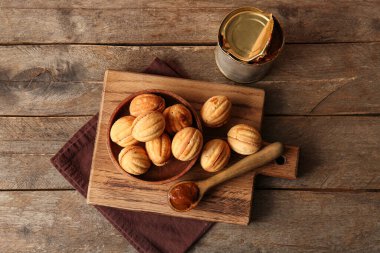 Lezzetli ceviz şekilli kurabiyeler ve ahşap zemin üzerinde kaynamış konserve süt dilimleme tahtası.