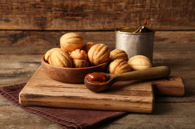 Lezzetli ceviz şekilli kurabiyeler ve ahşap zemin üzerinde kaynamış konserve süt dilimleme tahtası.