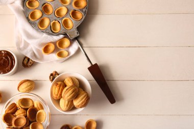 Lezzetli ceviz şekilli kurabiyeler ve hafif ahşap arka planda kaynamış süt karışımı.