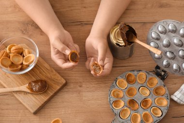 Lezzetli ceviz şekilli kurabiyeler, kaynamış süt ve ahşap arka planda pişirme formu, yakın plan.