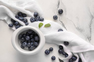 Mermer zemin üzerinde taze yaban mersinli peçete ve kase.