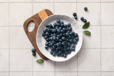 Ahşap kesme tahtası ve tabağı fayans zemininde taze yabanmersinli.