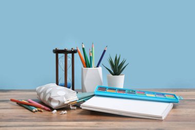 Kum saati olan bir kırtasiye seti ahşap masanın üzerinde renk duvarına karşı.