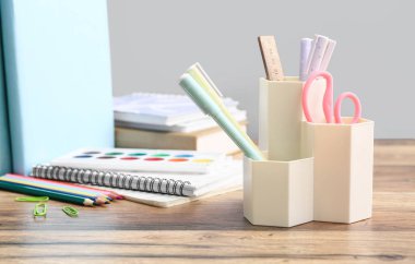 Gri duvara karşı ahşap masa üzerinde farklı kırtasiye seti