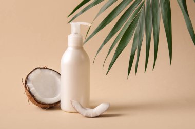 Hindistan cevizi kozmetik ürünü ve bej arka planda palmiye yaprağı.