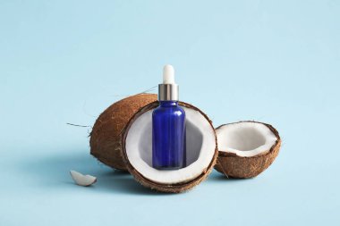 Mavi arka planda bir şişe hindistan cevizi kozmetik yağı.