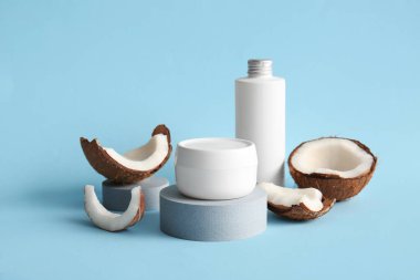 Mavi arka planda kavanoz ve bir şişe hindistan cevizi kozmetik ürünleriyle dekoratif podyumlar