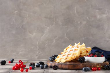 Gri arka planda masada böğürtlenli leziz Belçika waffle 'ları