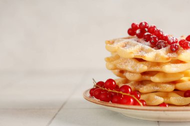 Kırmızı üzümlü lezzetli Belçika waffleları ve beyaz arka planda duran tabakta şeker tozu. Yakın çekim.