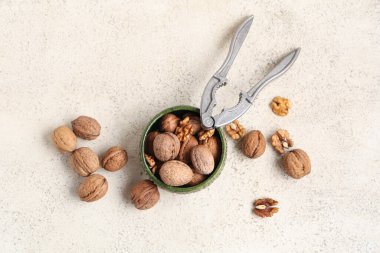 Beyaz arka planda ceviz ve fındık kıracağı olan bir kase.