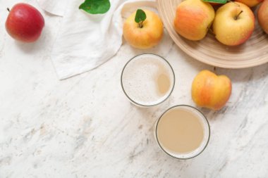 Taze elma kvass bardakları ve beyaz arka planda meyveler