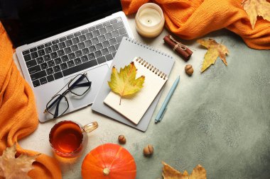 Modern dizüstü bilgisayarlı kompozisyon, not defterleri, bir fincan çay ve grunge arkaplanda sonbahar dekorasyonu