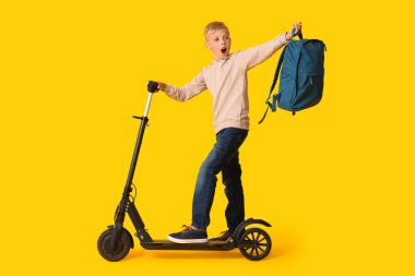 Modern elektrikli scooter 'ı ve sarı arka planda sırt çantası olan sevimli bir okul çocuğu.