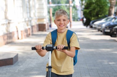 Modern elektrikli scooter 'ı ve sırt çantası olan sevimli bir okul çocuğu.