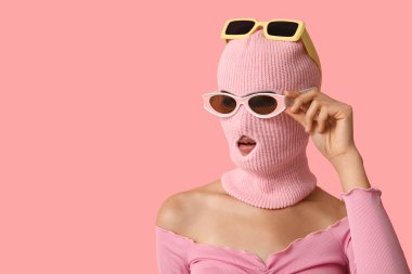 Kar maskeli, pembe arka planda güneş gözlüklü güzel bir kadın.